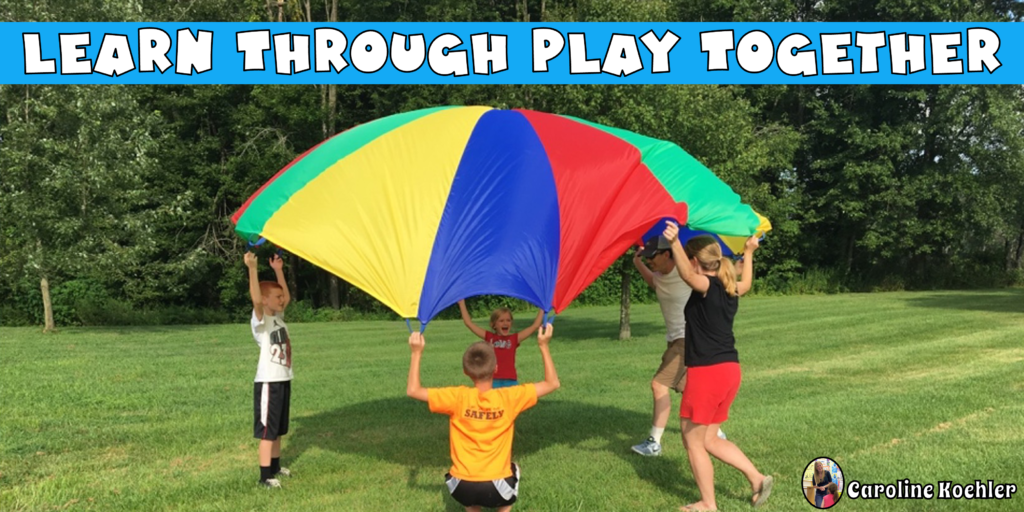 Kids playing with parents outside with a large colorful parachute.